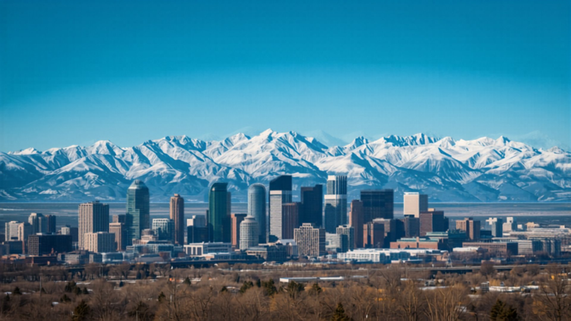 Denver skyline with snow-capped Rocky Mountains behind it